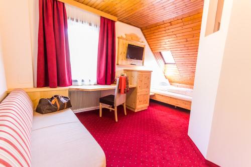 a bedroom with a bed and a desk and a window at Hotel Trattlerhof in Bad Kleinkirchheim