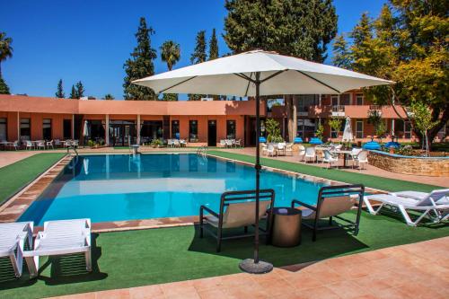 a swimming pool with chairs and an umbrella at Hotel Ouzoud Beni Mellal in Beni Mellal