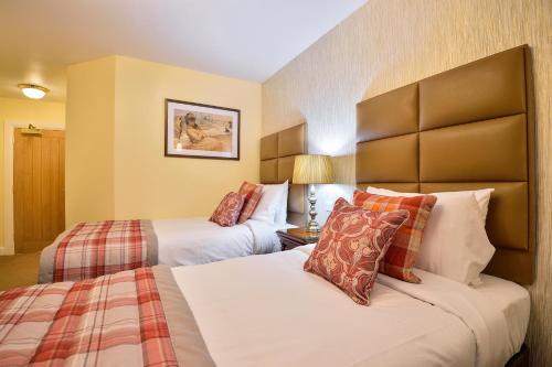 a hotel room with two beds and a lamp at The Coach and Horses in Worthing