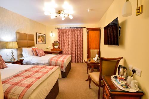 a hotel room with two beds and a desk at The Coach and Horses in Worthing