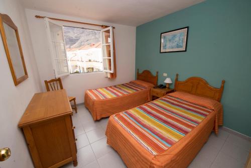 een slaapkamer met 2 bedden, een tafel en een raam bij Apartamentos Checkin Laurisilva in Valle Gran Rey