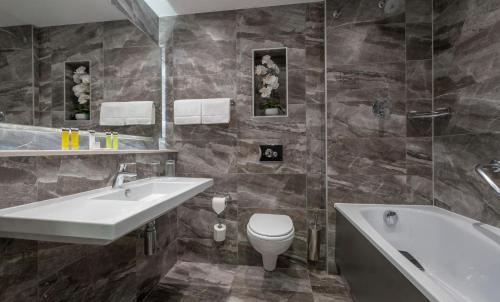 ein Badezimmer mit einem Waschbecken, einer Badewanne und einem WC in der Unterkunft Talbot Hotel Stillorgan in Stillorgan