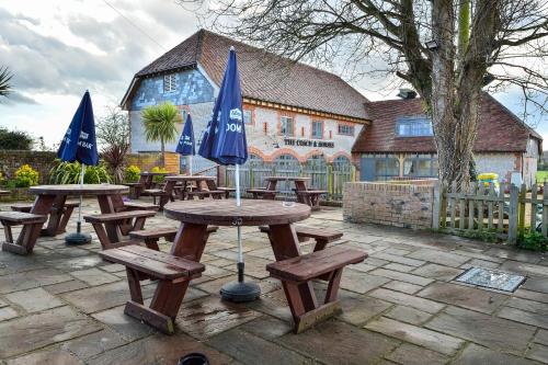 a group of picnic tables with blue umbrellas at The Coach and Horses in Worthing