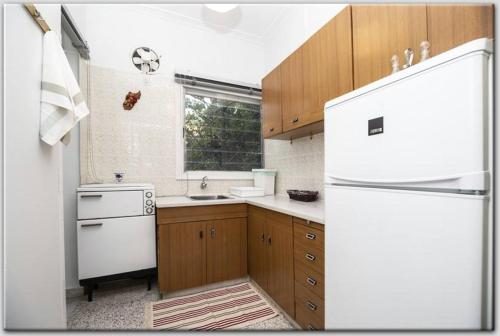 cocina con nevera blanca y armarios de madera en Anni's apartments 50m from the beach, en Agia Triada