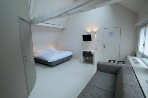 a white room with a bed and a couch at Hotel Matelote in Antwerp