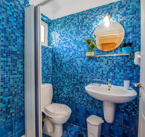 a blue tiled bathroom with a toilet and a sink at Gianthea Studios and Apt in Stalos