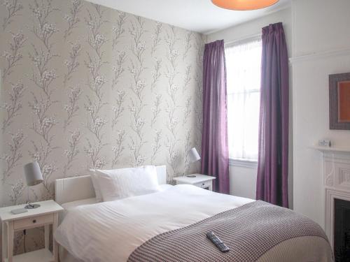 a bedroom with a bed and a window with purple curtains at Elmdon Lodge in Birmingham