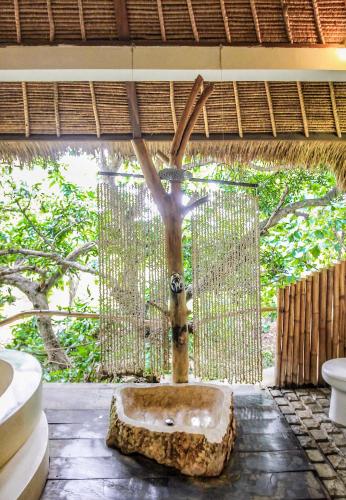 a bathroom with a tree in the middle of a room at La Cabane in Jimbaran