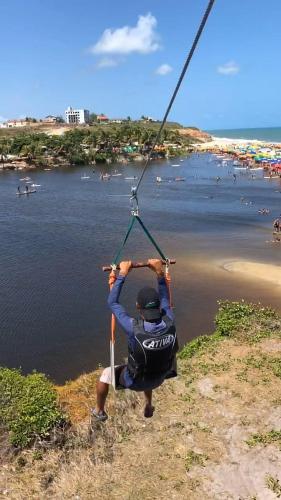a man in a swing over a body of water at Pousada Aconchego in Pitimbu