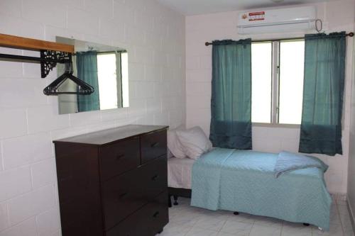 - une chambre avec un lit, une commode et un miroir dans l'établissement Lotopa Home, à Apia