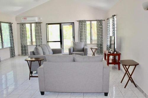 a living room with a couch and chairs and windows at Lotopa Home in Apia