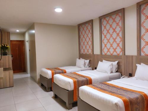 a hotel room with three beds and a television at Fairway Boutique Hotel - Kampala, Uganda in Kampala