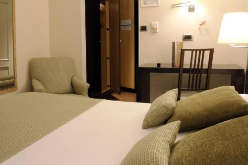 a bedroom with a bed and two chairs and a desk at Hotel Conde Duque Bilbao in Bilbao