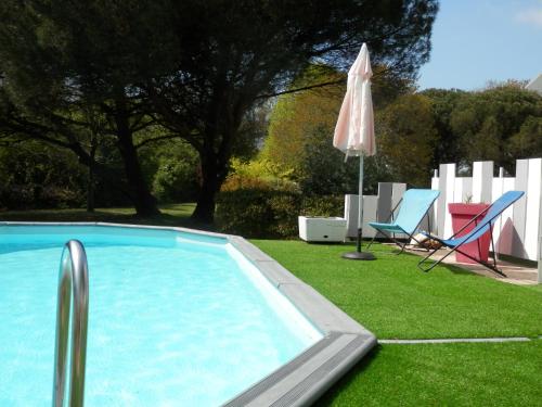 - une piscine avec un parasol, des chaises et une pelouse dans l'établissement La Désirade, à Saint-Laurent-de-la-Prée