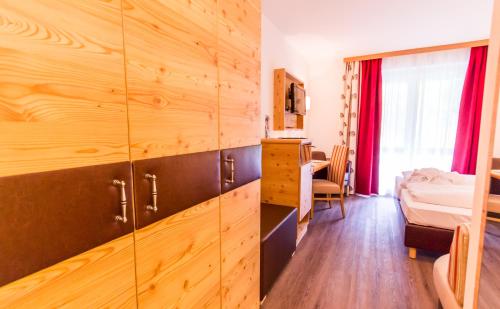 a bedroom with a wooden wall and a bed in a room at Hotel Trattlerhof in Bad Kleinkirchheim