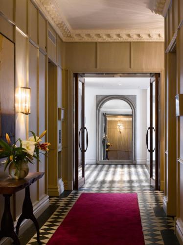 a hallway with a red rug and a hallway with a door at The Adria in London