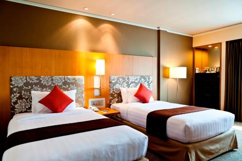 a hotel room with two beds with red pillows at Royal Princess Larn Luang - SHA Extra Plus in Bangkok