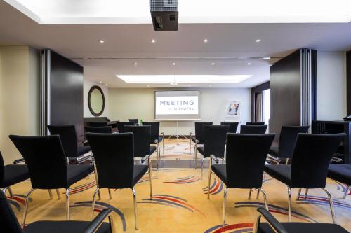 a meeting room with black chairs and a screen at Novotel Deira Creekside Dubai in Dubai