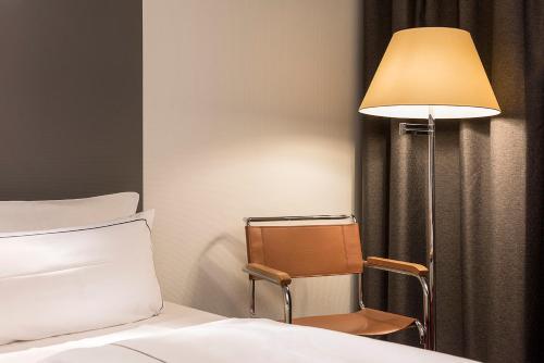 a bedroom with a bed and a lamp and a chair at Holiday Inn Berlin City-West by IHG in Berlin