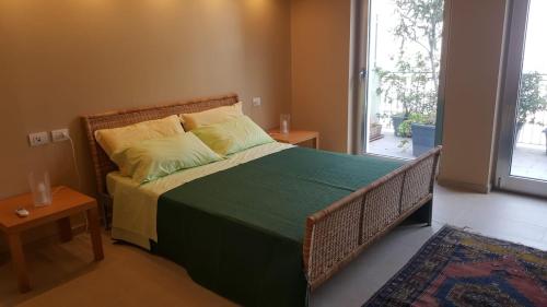 a bedroom with a bed with a green blanket and a window at Anteo holiday house in Riposto