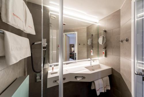 La salle de bains est pourvue d'un lavabo et d'un miroir. dans l'établissement IntercityHotel Magdeburg, à Magdebourg