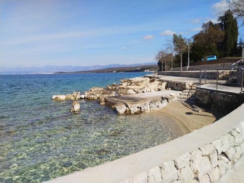 a large body of water with a stone wall at Apartman Helen in Malinska