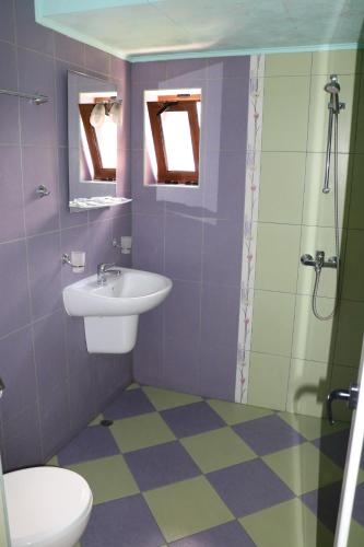 a purple bathroom with a sink and a shower at семеен хотел Визаж in Yambol