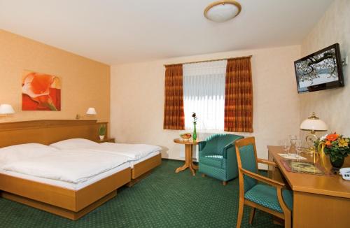um quarto de hotel com uma cama, uma secretária e cadeiras em HOTEL PÜNJER em Witzhave