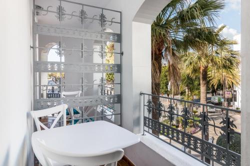 a balcony with a white chair and a window with palm trees at Boutique Hotel B51 in Marbella