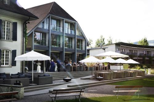 a building with tables and umbrellas in front of it at Hotel Schloss Hünigen in Konolfingen