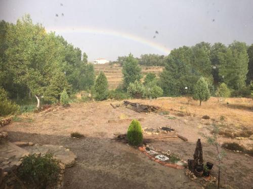 a rainbow in the sky over a field with trees at Monolocal rural con encanto in Valbona