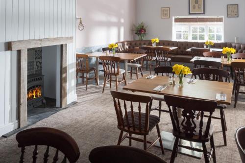 a restaurant with tables and chairs and a fireplace at Rashleigh Arms in St Austell