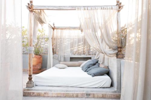 a canopy bed with white curtains in a bedroom at Riad Le Rihani in Marrakesh