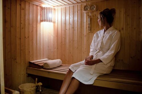 a woman sitting on a bench in a sauna at Savoy Crest Hotel Apartments in Dubai