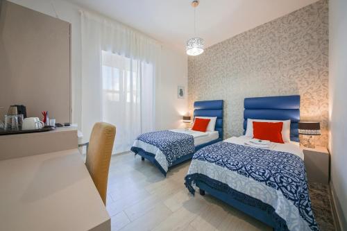 1 Schlafzimmer mit 2 Betten mit blauen und orangefarbenen Kissen in der Unterkunft San Martino Rooms in Pula