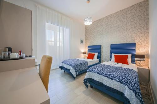 a bedroom with two beds with blue and orange pillows at San Martino Rooms in Pula