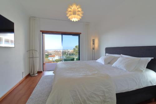una camera da letto con un grande letto con una grande finestra di Tim House a Olhão