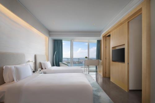 a hotel room with two beds and a television at The Mangrovetree Sanya Resort in Sanya