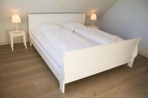 a white bed in a room with two lamps at 'Op de Borgt' met Finse Grill Kota in Wellen