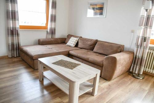 a living room with a brown couch and a table at Landgasthof Benjamin in Treffelstein