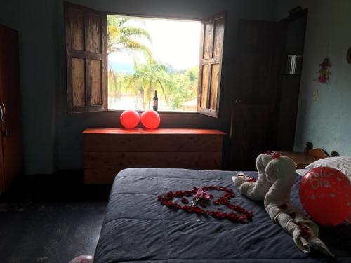 a bedroom with a bed with red balloons and a window at Casa finca típica the lake hotel in Guatapé