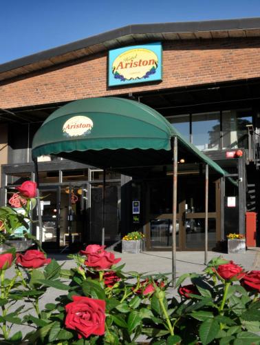 a green umbrella in front of a building with roses at Ariston Hotell in Lidingö