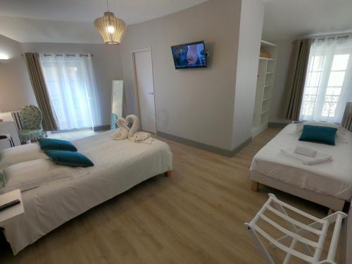 a bedroom with two beds and a tv on the wall at Le Home in Belvès