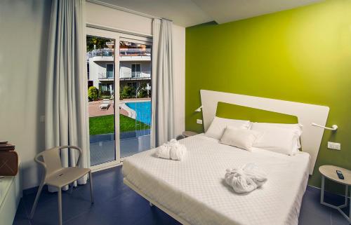 a bedroom with a white bed and a green wall at Ciclope Resort in Acitrezza