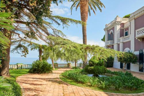 a house with a palm tree and a brick driveway at Villa Paola in Tropea