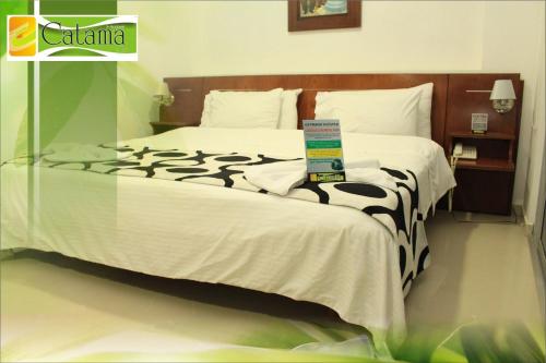 a bed with a black and white comforter on it at Hotel Catama Inn in Fusagasuga