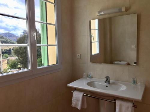 a bathroom with a sink and a mirror and a window at Hotel Du Vignoble in Patrimonio