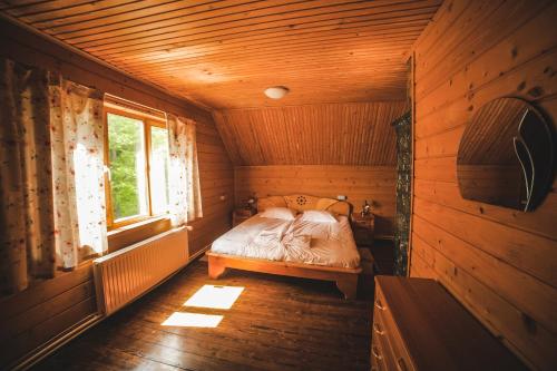 a bedroom with a bed in a wooden cabin at Karpatski Polonyny in Urych