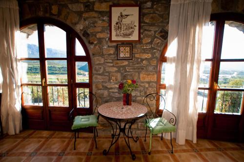 een tafel en stoelen in een kamer met een stenen muur bij Hotel Villa Románica in Aínsa