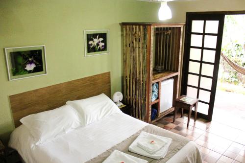 a bedroom with a bed in a room with a door at Gamboa Eco Refugio Pousada in Iporanga